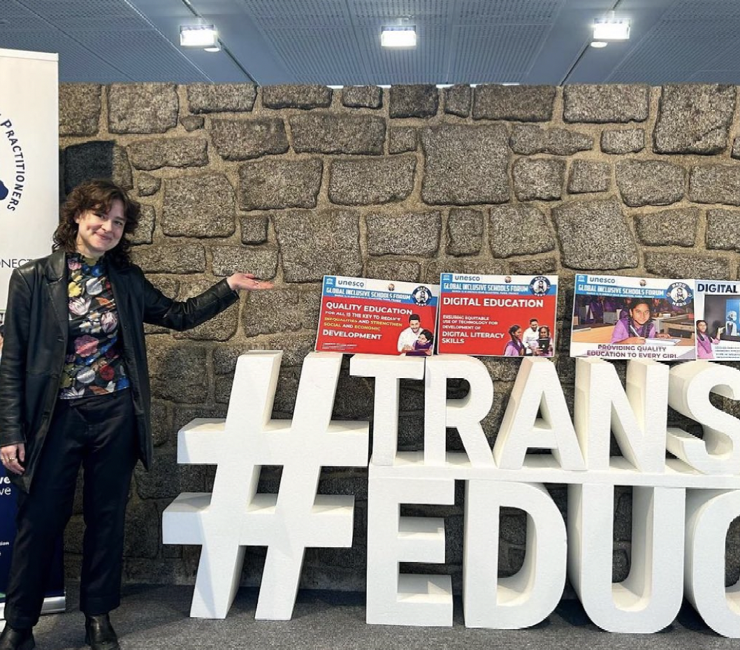 Sophie in front of a sign that reads "transforming education"